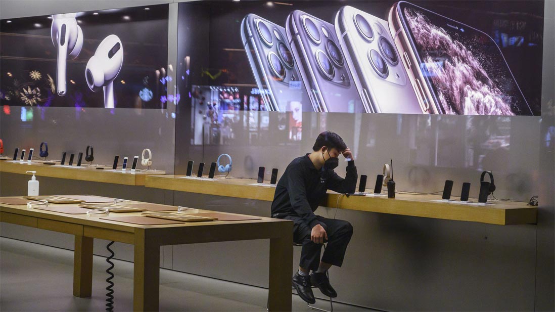 Apple employee wears a face mask in an empty Apple Store showroom