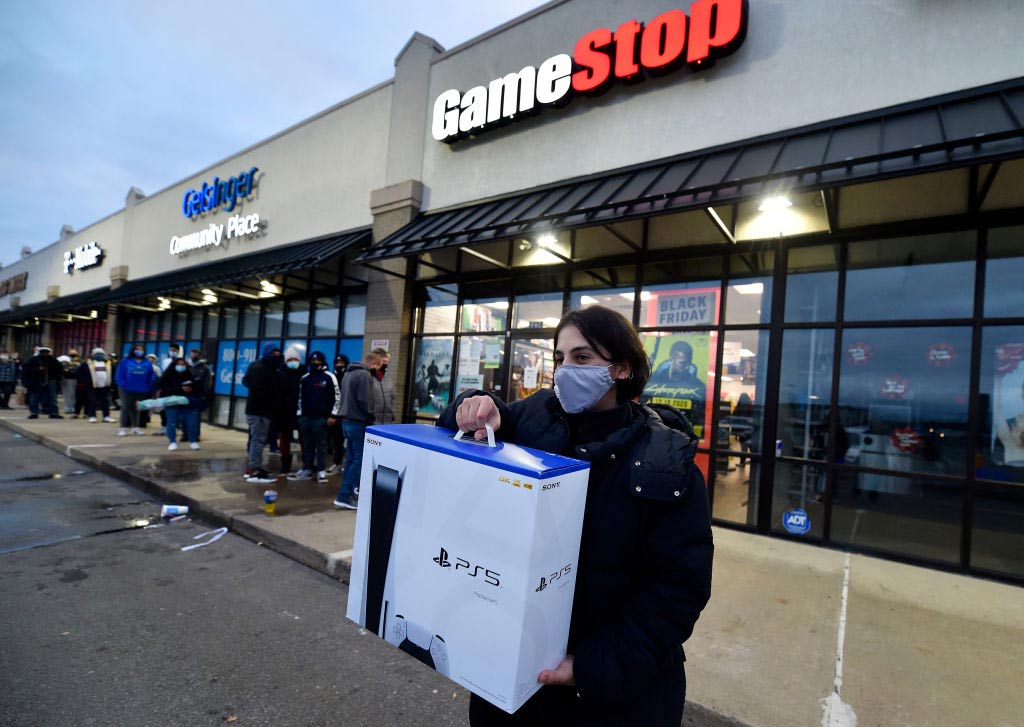 A person wearing a face mask leaves GameStop after buying a new Sony PlayStation 5 gaming console..