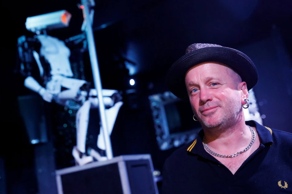 British artist Giles Walker poses next to his pole-dancing robot