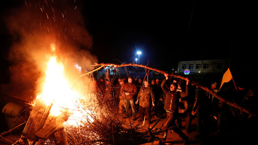Protesters in Ukraine set fire and create a barricade to stop the arrival of buses carrying evacuees from China